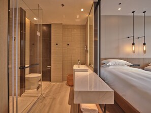 Un bagno moderno con box doccia in vetro, uno specchio grande e un mobile bagno in legno con lavabo.