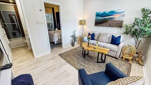 A modern living room with a sofa, coffee table, and a painting on the wall. - Beach Club | Renovated Condo | Steps to Crescent Beach | Heated Pool & Hot Tub | Siesta Key (Sarasota)