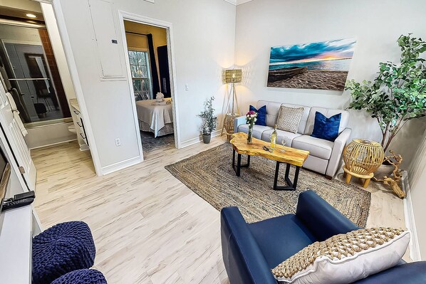 A modern living room with a sofa, coffee table, and a painting on the wall.