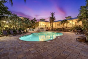 A swimming pool with lounge chairs and a building in the background. - Beach Club | Renovated Condo | Steps to Crescent Beach | Heated Pool & Hot Tub | Siesta Key (Sarasota)