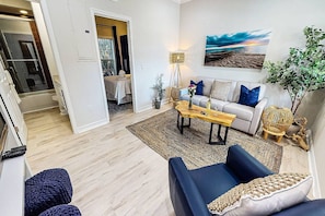 A living room with a sofa, coffee table, and a painting on the wall. - Beach Club | Crescent Beach | Pool & Hot Tub (Sarasota)