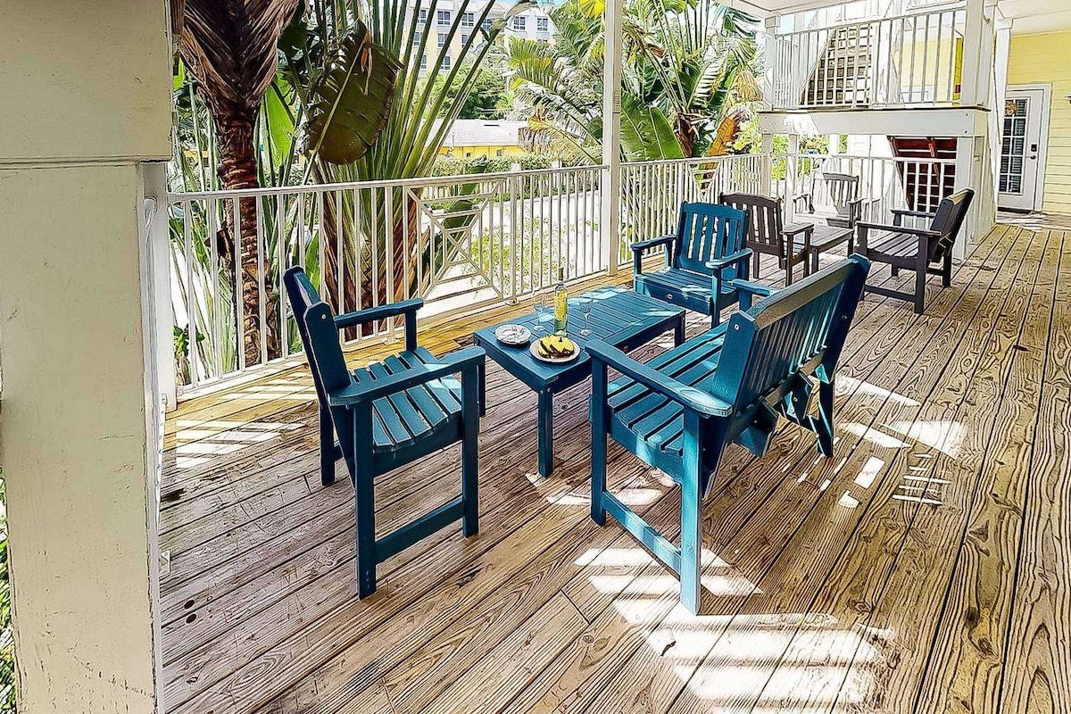 Een overdekt terras met houten vloer en blauwe stoelen.