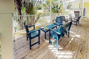 A covered outdoor seating area with wooden flooring and blue chairs. - Beach Club | Crescent Beach | Pool & Hot Tub (Sarasota)