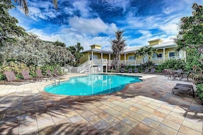 A swimming pool with lounge chairs and a building with a balcony. - Beach Club | Crescent Beach | Pool & Hot Tub (Sarasota)