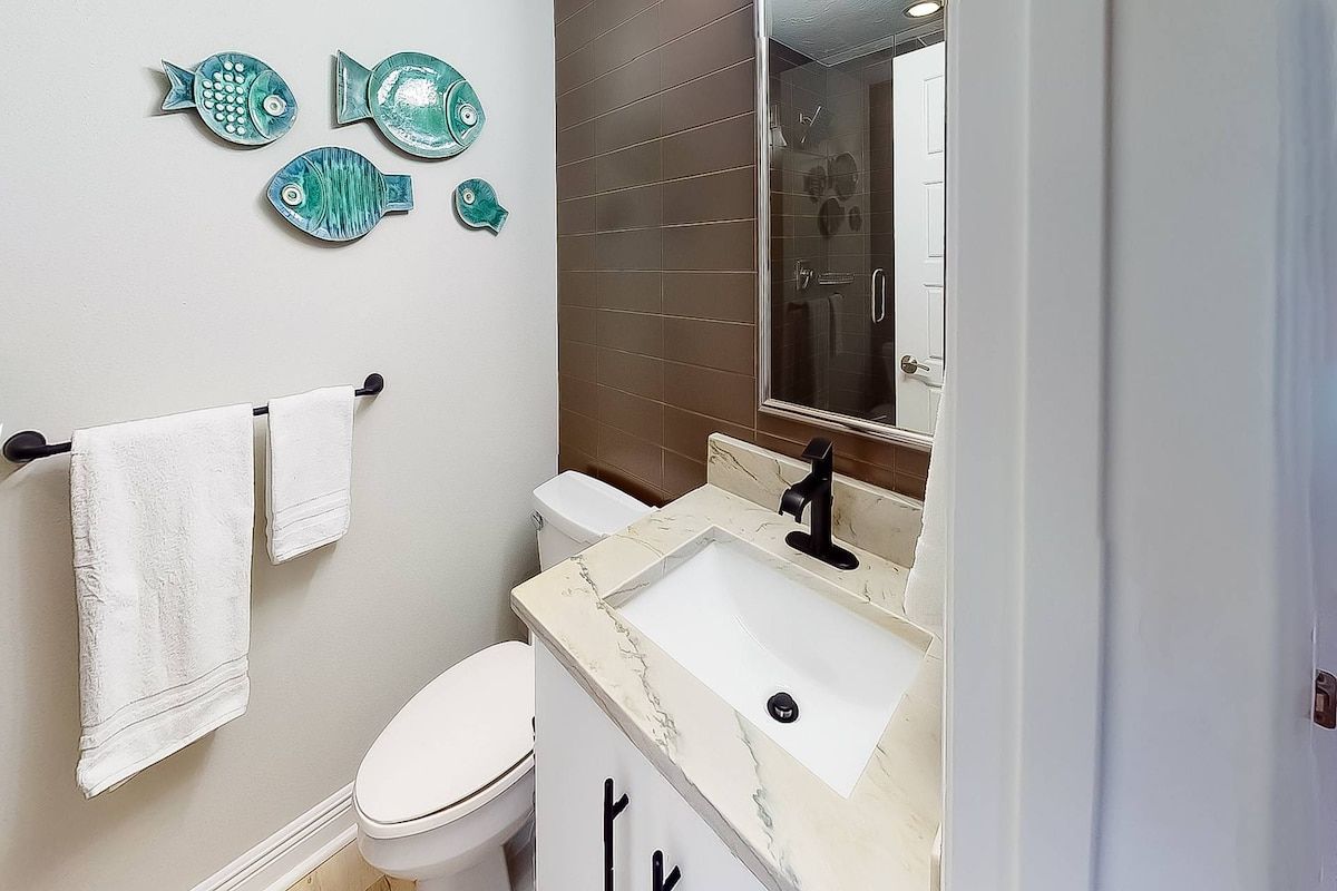 A bathroom with a toilet, sink, and a mirror.