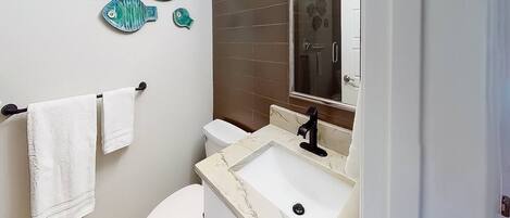 A bathroom with a toilet, sink, and a mirror.