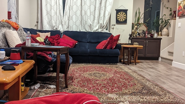 Un salon avec un canapé bleu foncé, un tapis rouge et une table basse en bois.