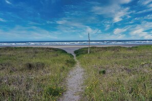 A coastal path leading to the beach with a clear sky.