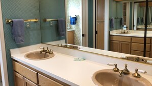 Une salle de bain avec un double vasque, deux robinets dorés, un grand miroir et des meubles en bois.