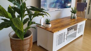 Ein Wohnzimmer mit einer Holz-Fernsehbank, einer großen Kübelpflanze und einem flachbildschirmfernseher an der Wand.