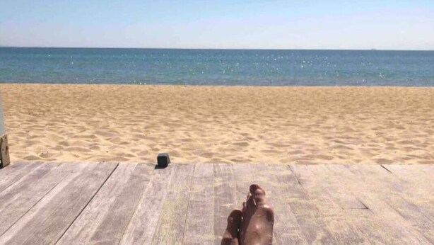 Eine Holzterrasse mit Blick auf den Strand und den Ozean.