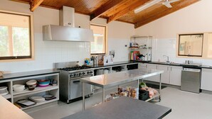 Een moderne keuken met een centraal eiland, roestvrijstalen apparatuur en houten balken in het plafond.