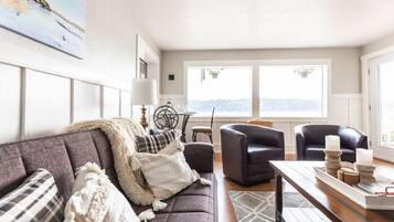 Un salon comprenant un canapé, deux fauteuils, une table basse et donnant sur l’extérieur.