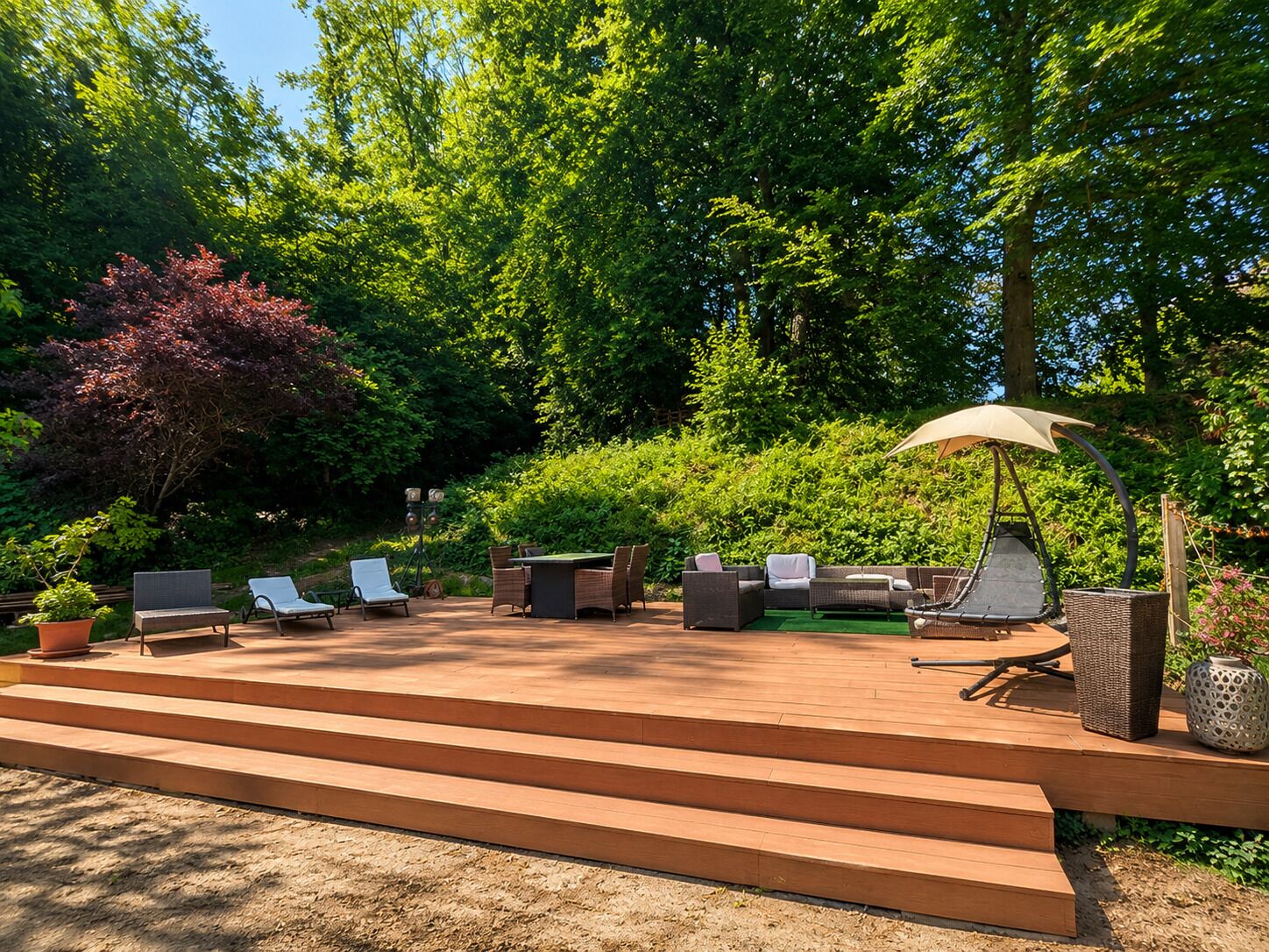 A patio with outdoor furniture, a pergola with an umbrella, and steps leading to the patio.