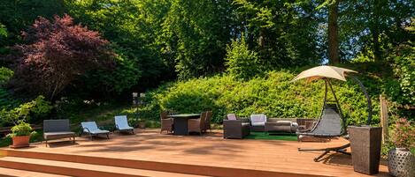 A patio with outdoor furniture, a pergola with an umbrella, and steps leading to the patio.