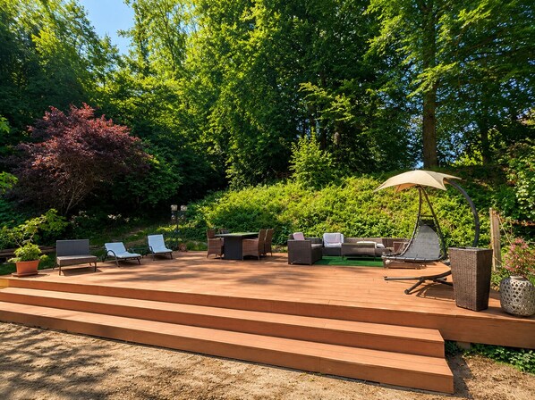 A patio with outdoor furniture, a pergola with an umbrella, and steps leading to the patio.