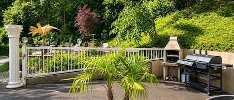 An outdoor patio area with a grill, seating, and a potted plant.