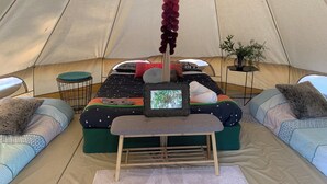 L’intérieur d’une tente, avec un lit, des oreillers, une petite table et une décoration suspendue.