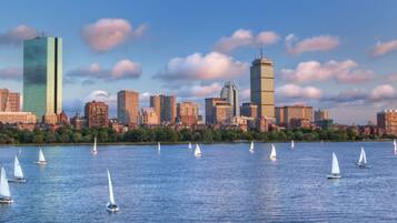 A city skyline with modern skyscrapers and sailboats on the water.