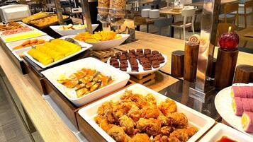 Un bufé con diversas opciones de comida, incluyendo pollo frito, frutas y postres.