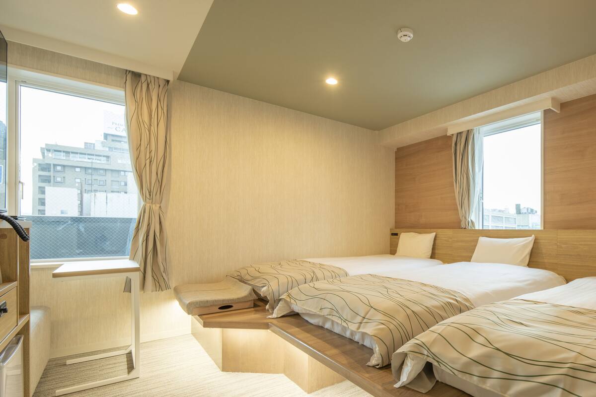 Une chambre d’hôtel moderne avec deux lits, un petit bureau et une vue sur la ville.