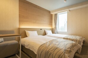 Une chambre d’hôtel avec deux lits, un bureau et une fenêtre.