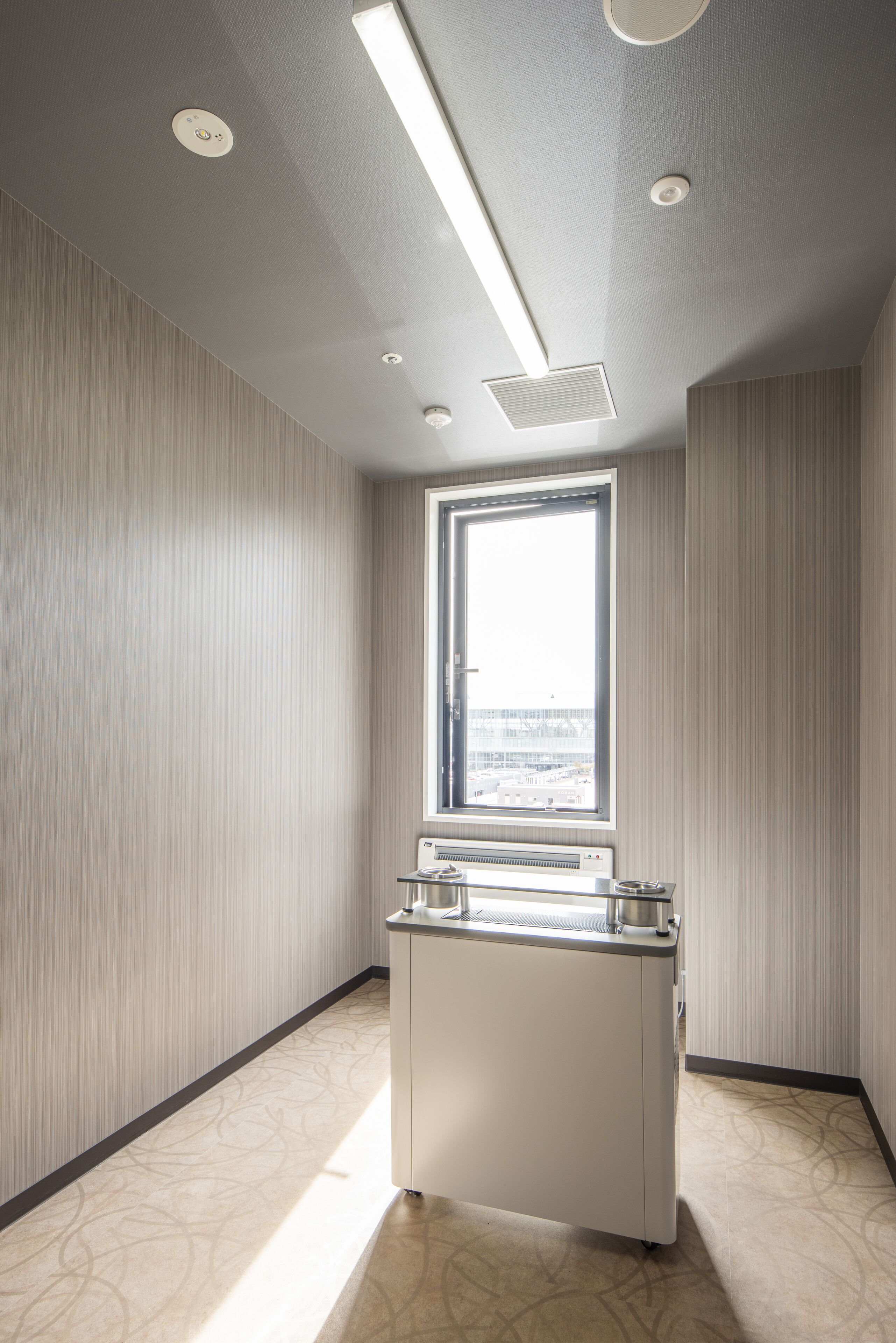 Una habitación de hotel con un ventanal grande, un minibar e iluminación empotrada en el techo.