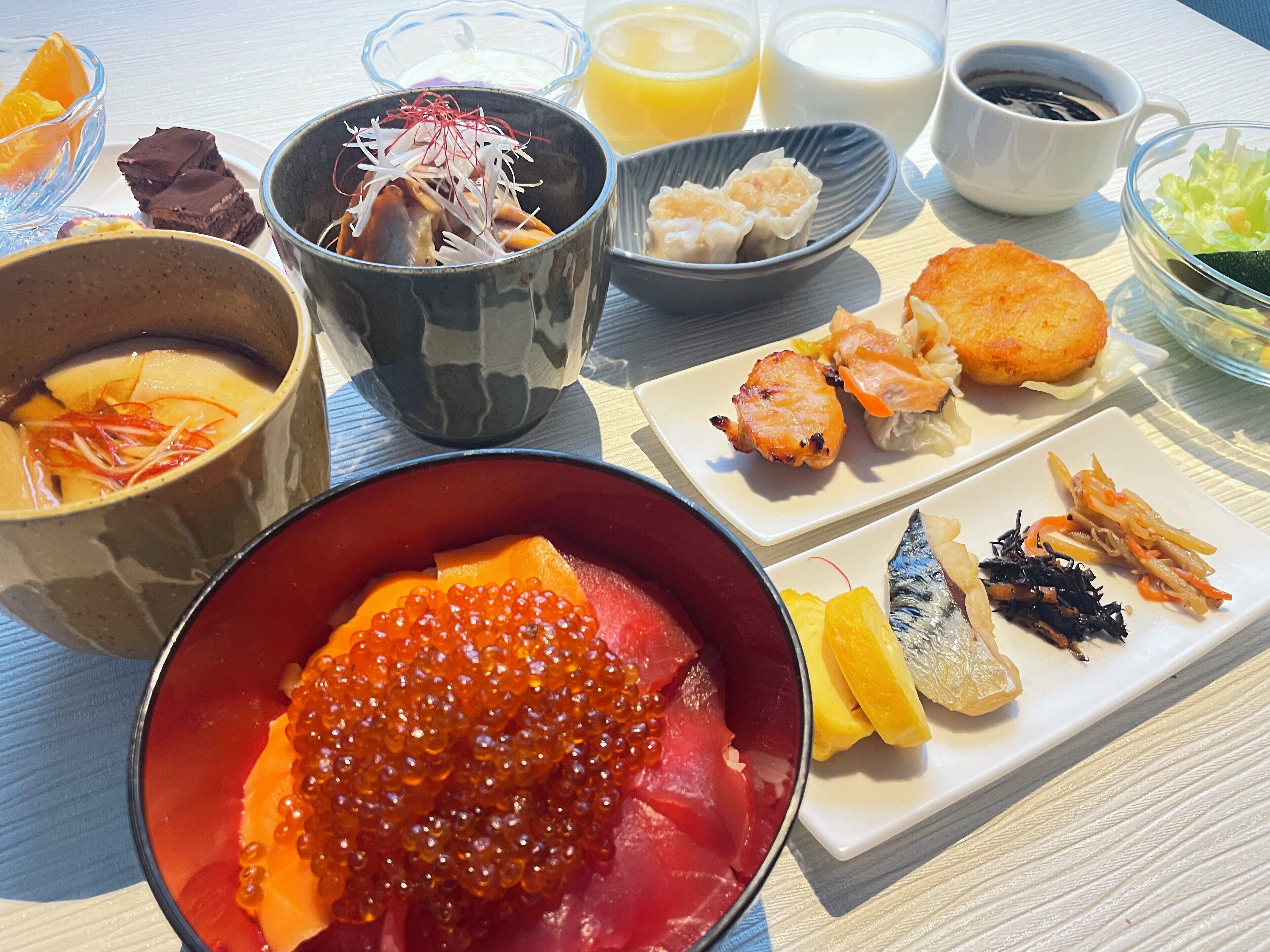 A variety of dishes including sashimi, tempura, and a bowl of soup.