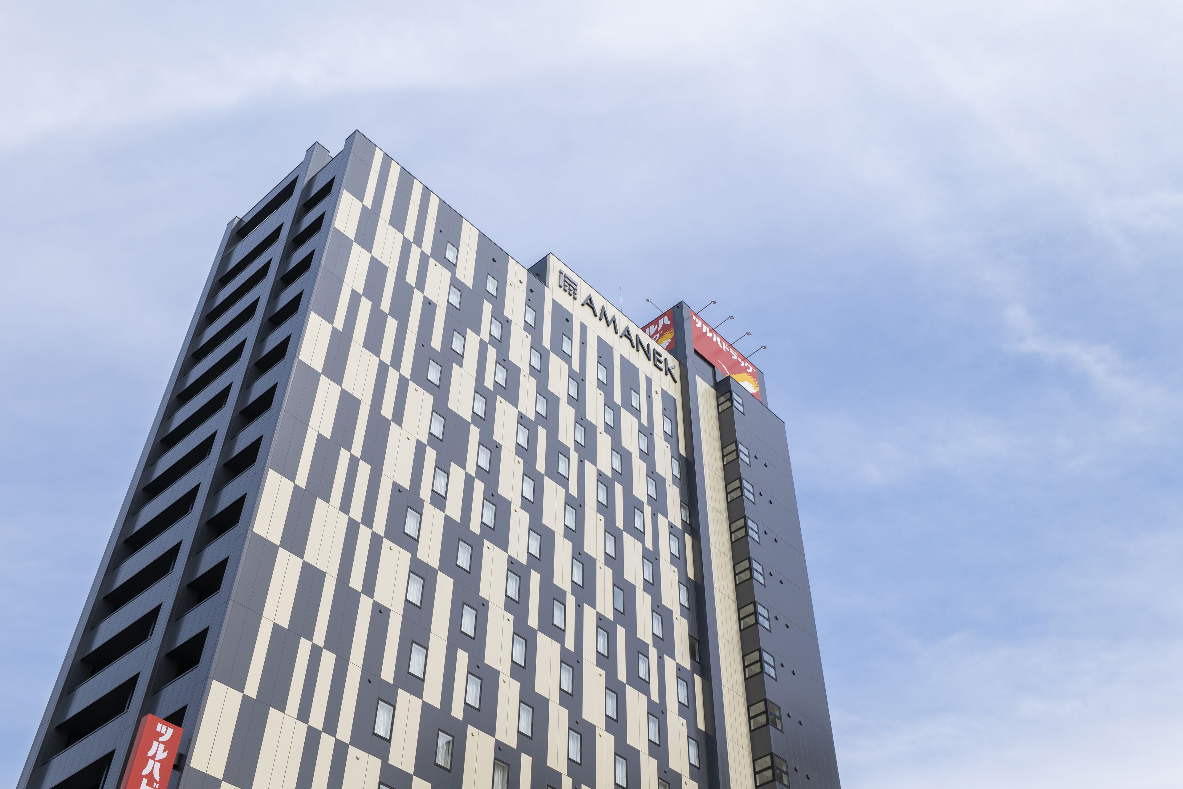 A tall building with a patterned facade and signage indicating it is a hotel.