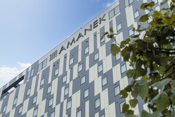A modern building with a grid-like facade and the name "AMANEK" prominently displayed.