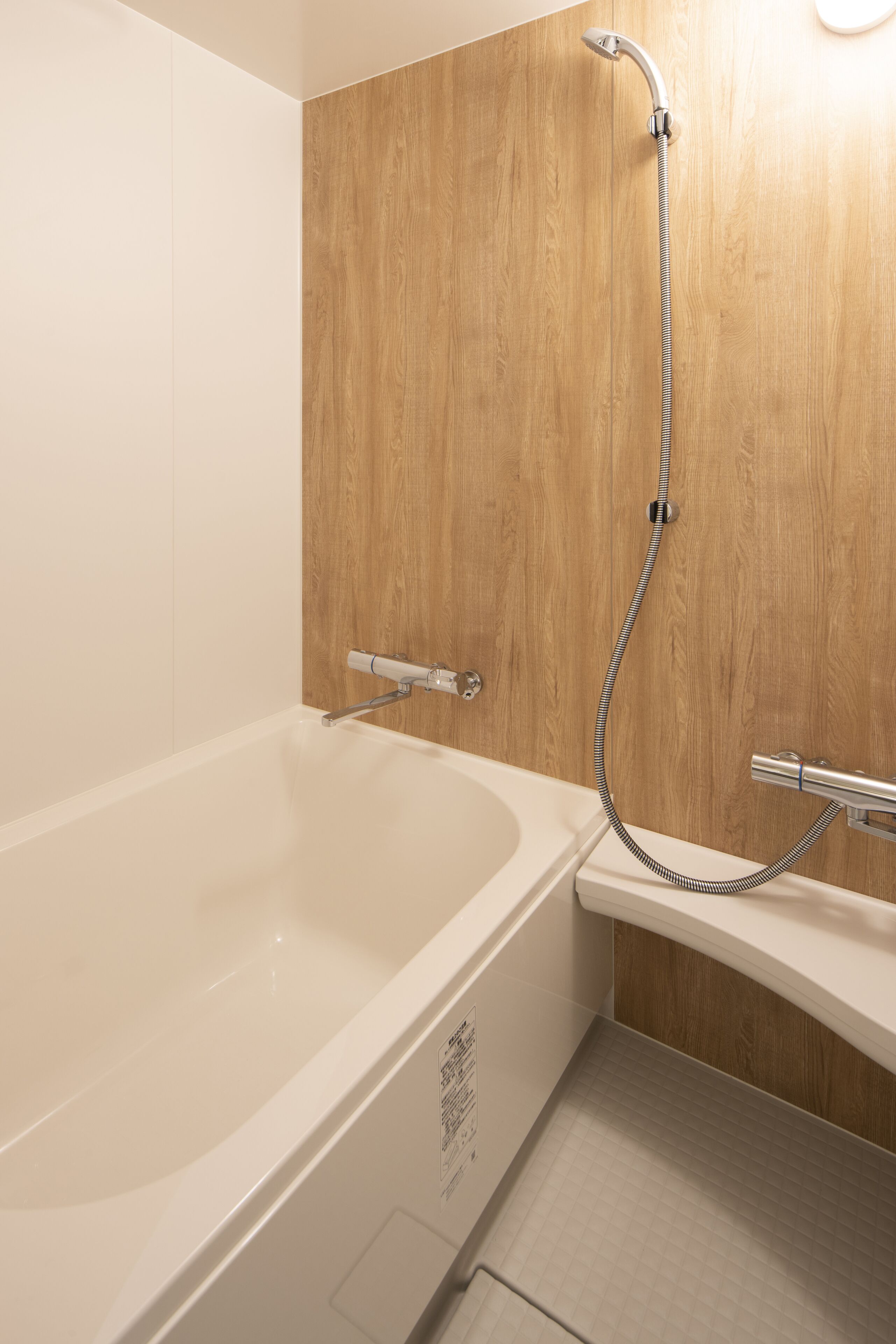 A modern bathroom with a wooden wall, a white bathtub, and a separate shower area.