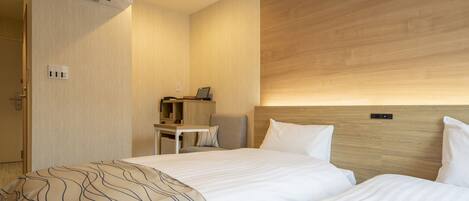 A hotel room with two beds, a desk, and a chair.