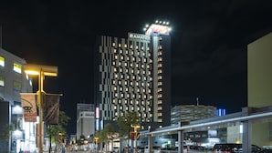 Een hoog hotelgebouw met een moderne gevel, verlichte ramen en een opvallend bord bovenaan.