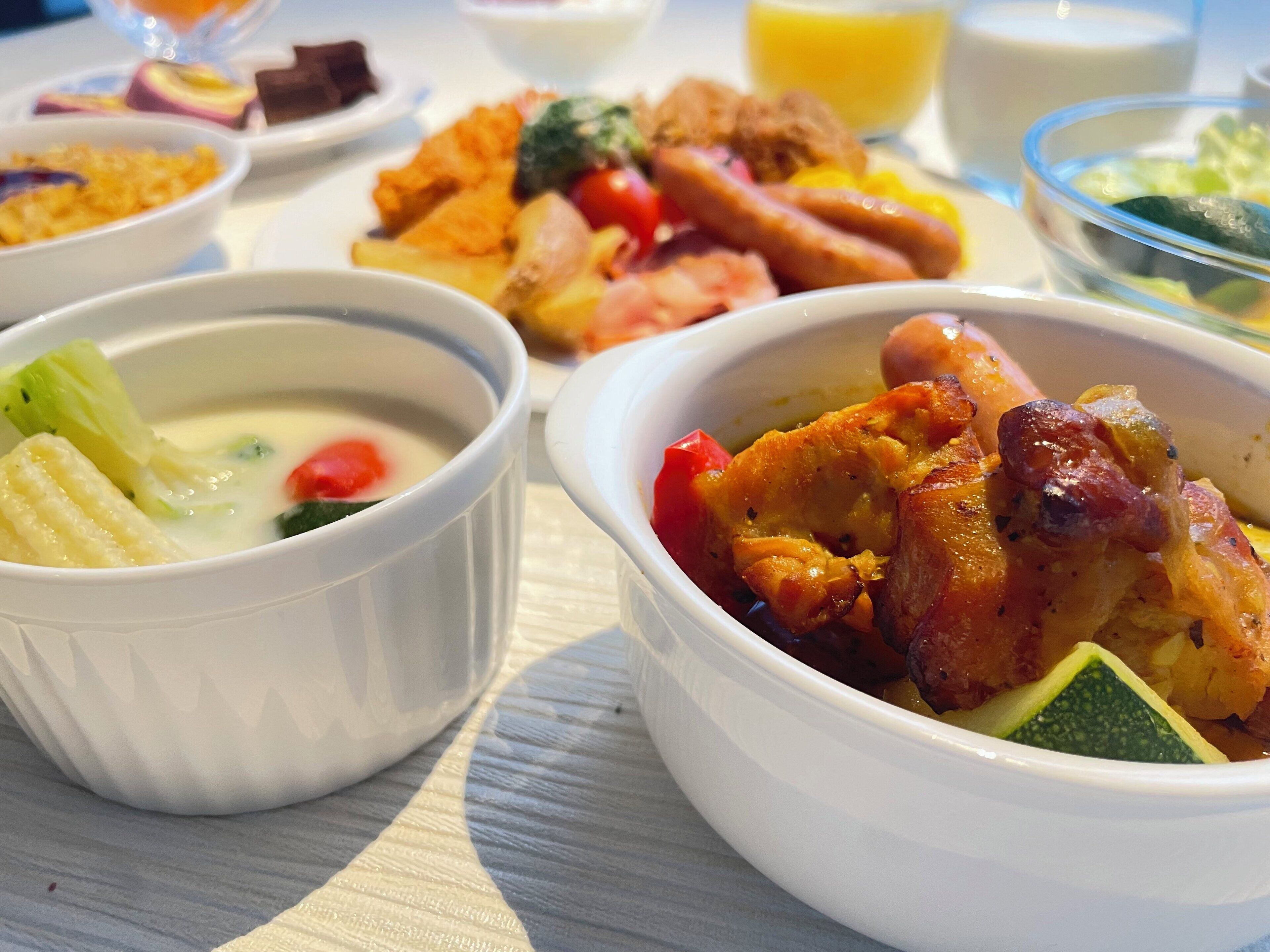 Una mesa con varios platos, incluyendo un tazón de sopa, un tazón de carne y un plato con frituras.