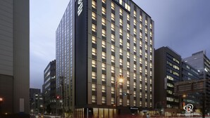 A modern hotel building with a prominent logo on the facade, multiple floors, and a well-lit entrance. - Daiwa Roynet Hotel Osaka Sakaisuji Honmachi PREMIER (Osaka)
