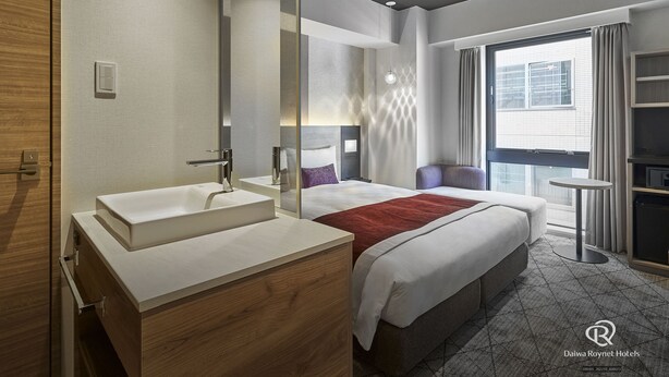 A modern hotel room with a large bed, a separate bathroom with a vanity, a small table, and a view of the city through the window. - Daiwa Roynet Hotel Osaka Sakaisuji Honmachi PREMIER (Osaka)