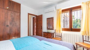 Slaapkamer met een bed, een houten garderobe, een bureau met stoel, een radiator en een raam met gordijnen.