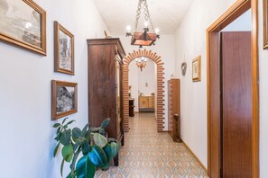 A hallway with patterned flooring, wooden doors, and a chandelier.