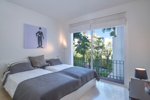 Une chambre à coucher avec un lit, un tableau, un balcon avec vue et une lampe.
