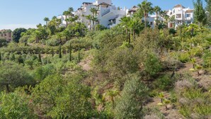 A hillside residential area with white buildings and palm trees. - Apartment "Seaview Flat Benahavis-Marbella" with Sea View, Pool, Wi-Fi, Terrace & Garden (Benahavis)
