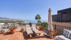 Une terrasse avec deux fauteuils, un canapé et des plantes en pot.