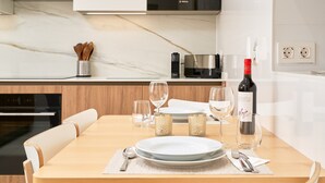 Une cuisine moderne avec une table à manger pour deux personnes, un four à micro-ondes de la marque Bosch et une bouteille de vin.