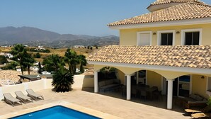 A residential property with a swimming pool, outdoor seating, and a view of distant mountains.