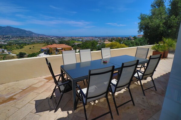 Un patio al aire libre con mesa y sillas, con vistas a un paisaje pintoresco de un pueblo y montañas.