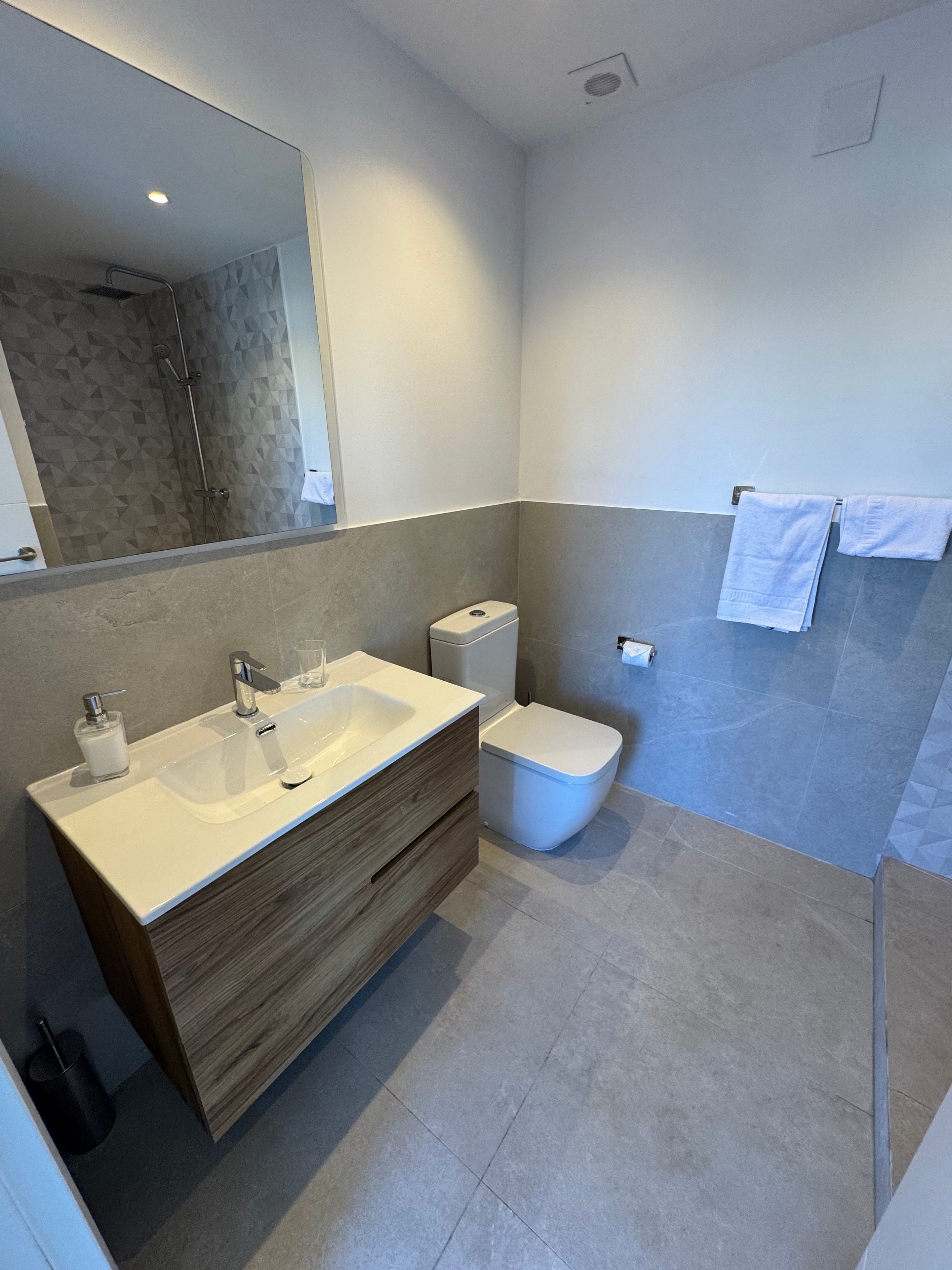 Une salle de bain moderne avec un meuble-lavabo à deux vasques, des toilettes et un espace douche.