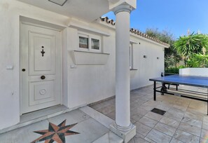 A white building with a door, a small window, and a table tennis table.