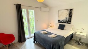 A bedroom with a bed, bedside tables, a red chair, a window with curtains, and a ceiling light fixture. - 'Nice and Spacius Villa near Fuengi' with Sea & Mountain View, Pool, NO under 40 (Mijas)