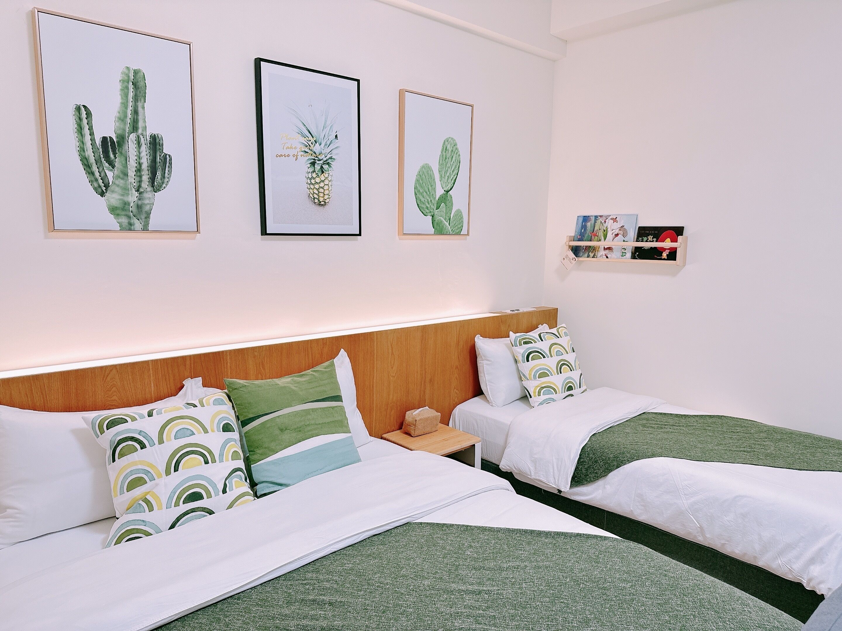 Quarto de hotel com duas camas, uma cabeceira de madeira e três quadros na parede.