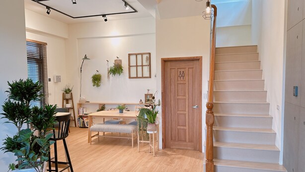 A modern interior with a wooden staircase, a dining area with a table and chairs, and a bookshelf. - Gardenstay (Luodong)