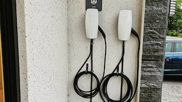 A Tesla electric vehicle charging station with a sign indicating it is for Tesla vehicles, a TPC charging icon, and a wall connector box.
